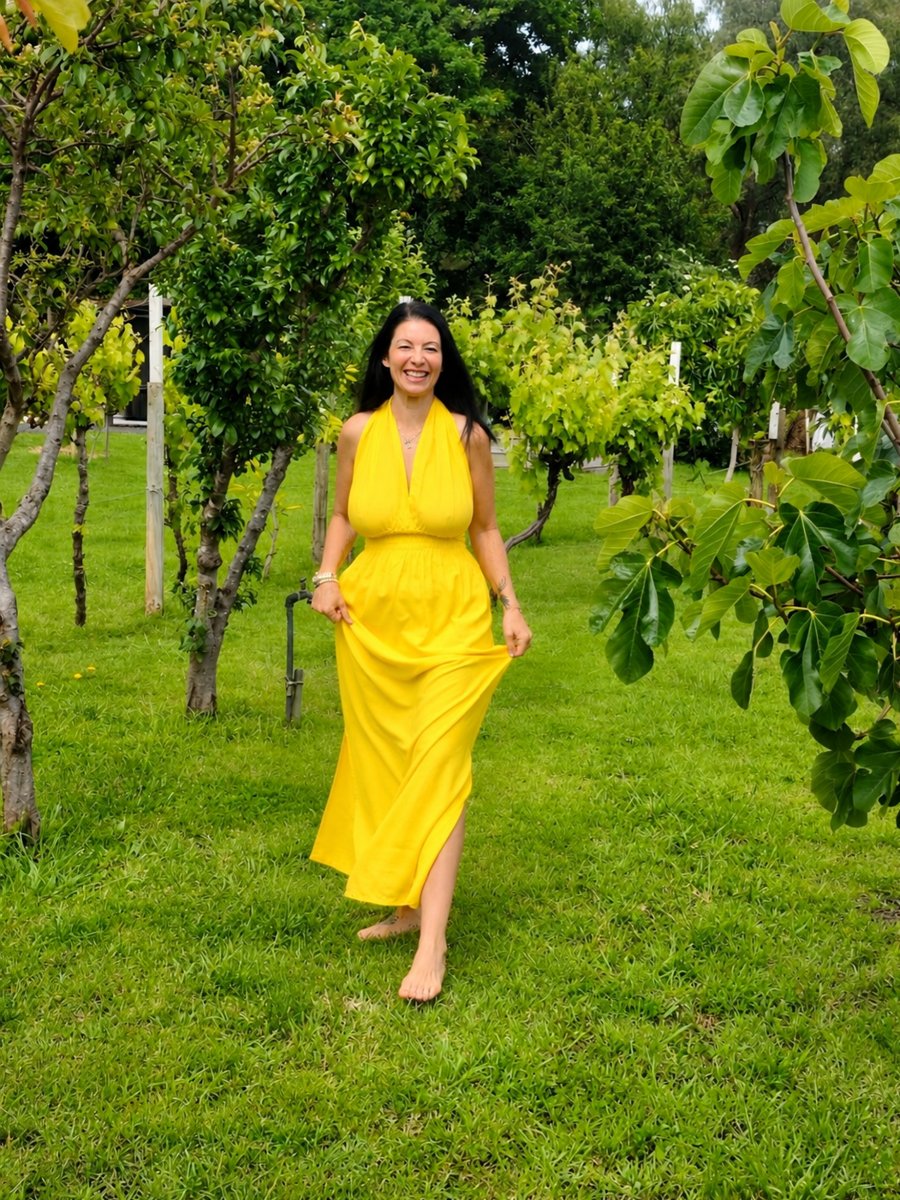 Janina, founder of Wonderfully AI, smiling as she walks barefoot through a green garden in a yellow dress